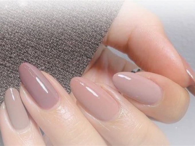 Glossy mauve-taupe almond nails resting on soft grey fabric