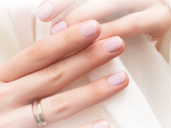 Soft blush manicure on short nails against cream silk