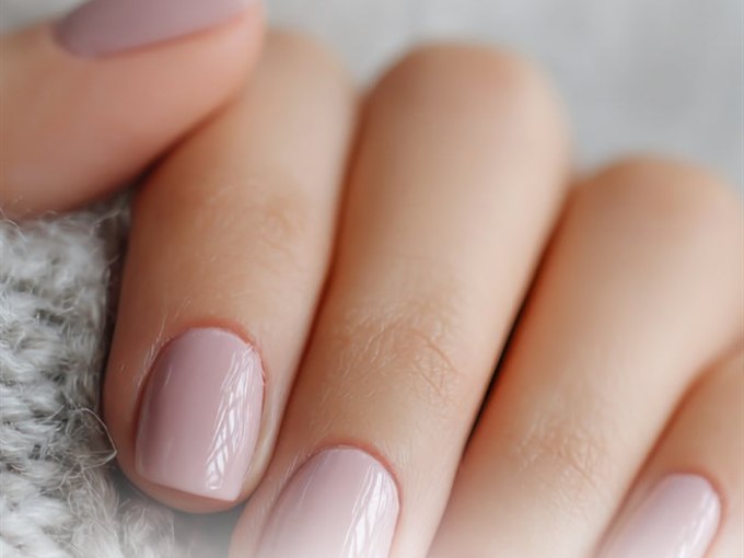 Soft pink manicure on short natural nails against knitwear